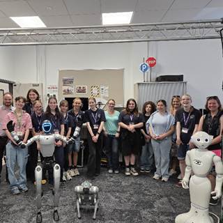Year 10 girls standing with a collection of robots at their Girls into Electronics day